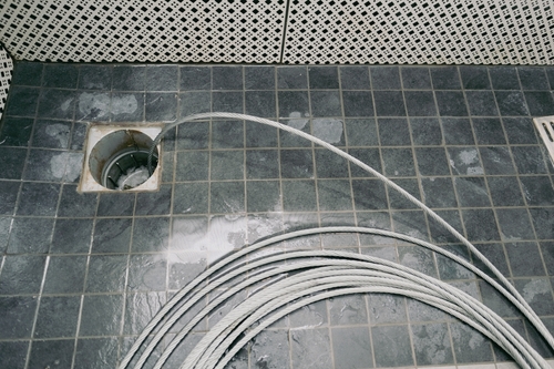 A slow drain might not seem like a big deal at first. The water takes a few extra seconds to disappear after you wash dishes or step out of the shower. But in Oakley, CA, slow drains almost always get worse if you leave them alone. The combination of Delta-region water quality, expanding neighborhoods with shared sewer mains, and the typical buildup inside residential pipes means that a sluggish drain today could become a full backup next month. If you have tried store-bought drain cleaner and the problem came back within a few weeks, that is a sign the clog is deeper in the line. Professional drain cleaning in Oakley addresses the root cause, not just the symptom. What Causes Frequent Drain Clogs in Oakley Homes There is no single reason drains clog, but certain factors show up repeatedly in the homes we service throughout eastern Contra Costa County. Grease is the number one kitchen drain killer. Cooking oil, bacon fat, and even residue from sauces coat the inside of your drain pipe. It solidifies as it cools, trapping food particles and creating a narrower and narrower passageway for water. Most Oakley homeowners do not realize the grease is building up until the sink will not drain at all. Tree roots are the biggest threat to sewer lines. Oakley yards often have mature trees, and the roots seek out moisture wherever they can find it. Even a hairline crack in your sewer lateral gives roots a way in. Once inside the pipe, they grow and expand until the pipe is partially or fully blocked. This is one of the most common reasons we deploy hydro jetting — the high-pressure water cuts through roots and flushes them out of the line. Mineral scale from Delta water adds another layer to the problem. The Contra Costa Water District sources water from the Sacramento-San Joaquin River Delta, and the dissolved minerals in that water leave deposits inside your pipes over time. Those deposits make it easier for grease, hair, and debris to catch and accumulate. Bathroom drains deal with a different cocktail of buildup. Hair, soap scum, and toothpaste combine into a sticky mass that clings to the walls of the pipe. Shower drains are especially prone to this because they handle high volumes of water mixed with body oils and hair every day. Why Store-Bought Drain Cleaners Do More Harm Than Good Chemical drain cleaners like Drano and Liquid-Plumr are marketed as quick fixes. They can dissolve certain types of clogs near the surface of the drain opening. But they come with serious trade-offs. The caustic chemicals generate heat inside the pipe. In older PVC or ABS plastic pipes, that heat can soften and warp the material. In older cast iron or galvanized steel pipes, the chemicals can accelerate corrosion. Over time, repeated use of chemical drain cleaners weakens the pipe itself, creating cracks and leaks that cost far more to repair than a professional drain cleaning would have. Beyond the pipe damage, chemical cleaners do not reach deep clogs. If the blockage is 20 or 30 feet down the line — which is common with tree root intrusion or a sewer main backup — the chemicals never even contact the clog. You end up with a pipe full of toxic chemicals sitting on top of the same blockage. The California Department of Toxic Substances Control classifies many chemical drain cleaning products as hazardous materials that require special disposal. Pouring them down your drain sends those chemicals into the wastewater system that eventually flows back into the Delta waterways. How Professional Drain Cleaning Works A licensed plumber uses mechanical and hydraulic methods to clear clogs without chemicals. The two most common approaches are cable snaking and hydro jetting. Cable snaking, sometimes called augering or rootering, uses a flexible metal cable with a cutting head at the tip. The plumber feeds the cable into the drain and through the pipe, breaking up the clog mechanically. This works well for localized blockages like a clump of hair in a bathroom drain or a food mass in a kitchen line. Hydro jetting takes it a step further. A specialized nozzle attached to a high-pressure hose is inserted into the pipe. Water pressure typically between 3,000 and 4,000 PSI scours the entire interior wall of the pipe, removing grease, mineral scale, tree roots, and debris. The result is a pipe that is as close to its original diameter as possible. If you have had recurring clogs in the same drain, hydro jetting is almost always the long-term solution. Before either method, a good plumber starts with a sewer camera inspection to see exactly what is causing the problem and where it is located. There is no reason to guess when a camera can show you the condition of the pipe in real time. Signs You Need Professional Drain Cleaning Not every slow drain is an emergency, but waiting too long turns a routine service call into a costly repair. Here are the signs Oakley homeowners should watch for. Water pools around your feet in the shower instead of draining as fast as it flows. Gurgling sounds come from the toilet or sink when you are not using them. The kitchen sink takes longer to drain every week. Multiple fixtures in the house are draining slowly at the same time, which usually points to a main line issue rather than an individual drain. Foul odors coming from the drain are a clear signal that organic material is decomposing inside the pipe. If you notice a sewage smell outside near your sewer cleanout, the problem may be in the lateral line connecting your home to the city main. Water backing up into a floor drain, bathtub, or washing machine drain is the most urgent sign. When waste water has nowhere to go, it comes back up through the lowest drain in the house. This requires immediate attention from a professional — contact our team right away if this is happening. Prevent Clogs Before They Start A few simple habits go a long way. Never pour grease or oil down the kitchen sink. Use a mesh strainer over shower drains to catch hair. Run cold water for 15 seconds after using the garbage disposal to flush food particles fully through the line. For Oakley homes with mature trees near the sewer lateral, consider scheduling a preventive hydro jetting service every 12 to 18 months. Clearing roots before they grow large enough to crack the pipe is far cheaper than a sewer line replacement. Quality Plumbing & Rooter provides drain cleaning throughout Oakley and surrounding communities including Brentwood, Antioch, and Knightsen. Call (925) 584-1951 for same-day service.